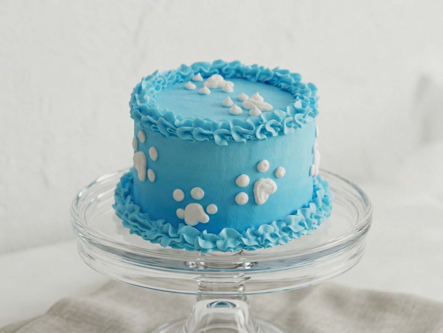 Sky blue dog birthday cake with white frosting paw prints